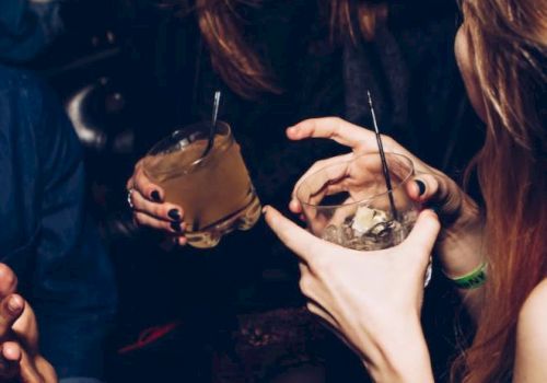 People are holding drinks and socializing, with one person seen laughing. The scene appears to be lively and possibly taken at a party or social gathering.